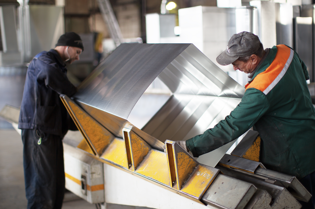 Two workers make metal ventilation pipes workshop factory